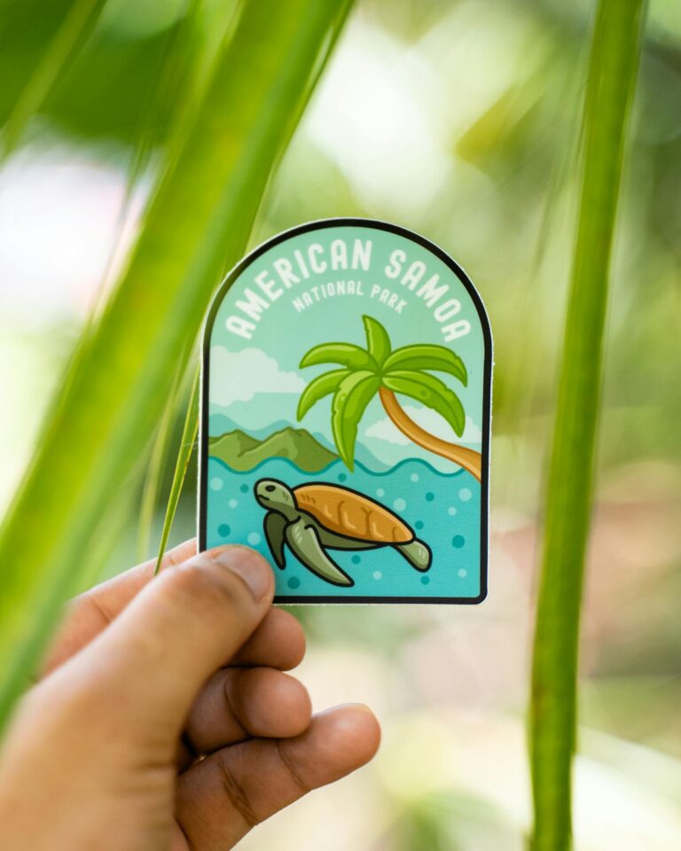 Close-up of a hand holding an American Samoa National Park sticker with tropical design.